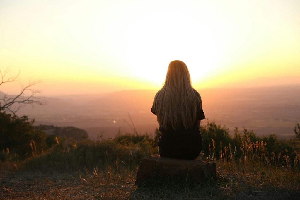woman alone sunset looking out over a vast field